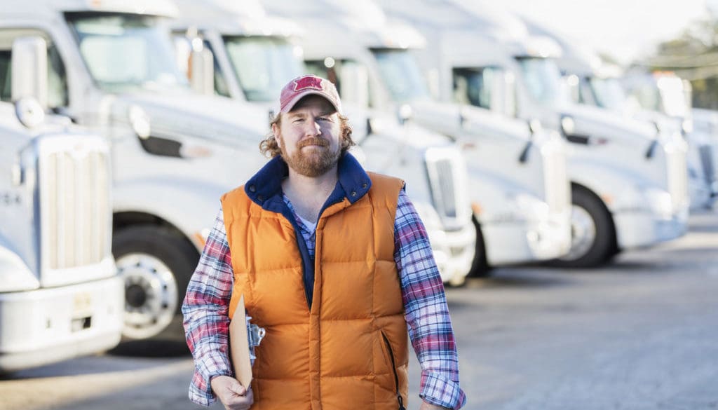 Man standing in front of semi-truck fleet